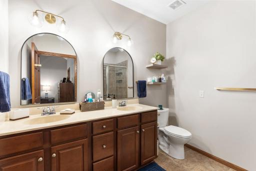 Private primary ensuite bathroom featuring a dual vanity, all-new modern arched designer mirrors, upgraded lighting, and stylish custom wood floating display shelving!