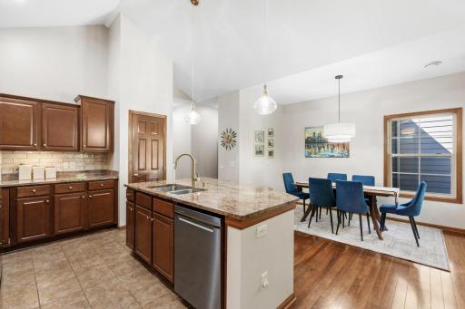 Another exceptional view of the gourmet kitchen and open dining area, highlighting the rich cabinet storage, sleek tile flooring, and brand-new designer lighting updates!