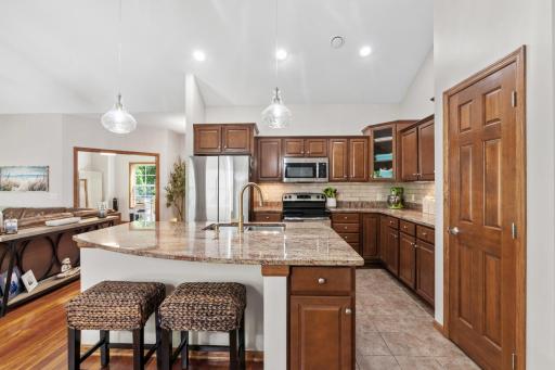 Gourmet chef's kitchen featuring an expansive center breakfast bar island, beautiful rich cabinetry, and a pair of brand-new, high-end designer glass pendant light fixtures!