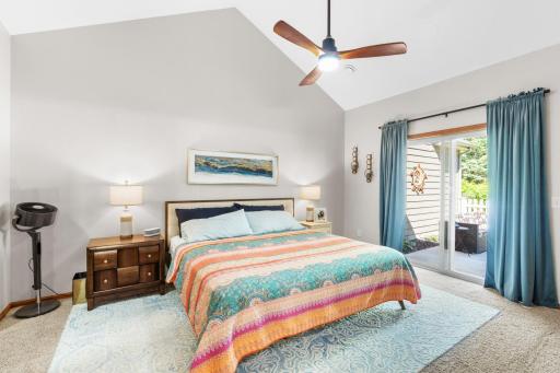 Spacious primary bedroom suite complete with dramatic vaulted knockdown ceilings, fresh contemporary paint, a modern ceiling fan, and private sliding glass door access directly to the rear patio!