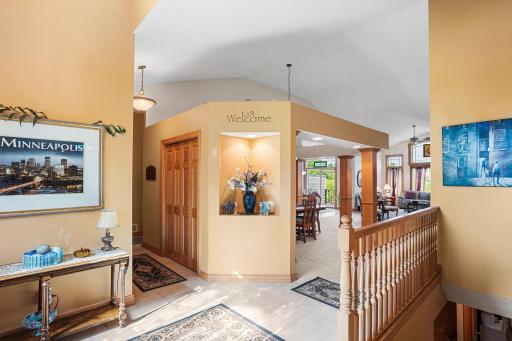 A dramatic two-story foyer with tile flooring, soaring ceilings, architectural niches, and warm woodwork creates a welcoming first impression.