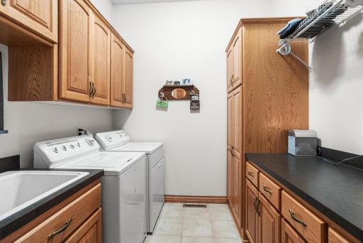 The main-level laundry room includes extensive cabinetry, a utility sink, folding counter, pantry storage, and space to keep household tasks organized.