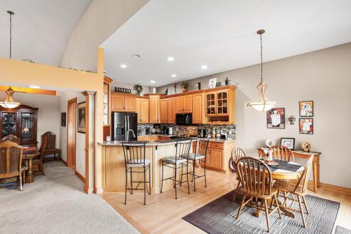 The kitchen offers abundant cabinetry, granite countertops, a center island with seating, recessed lighting, and an informal dining area overlooking the backyard.