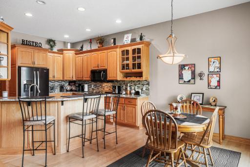 Granite countertops, a tile backsplash, raised-panel cabinetry, and a breakfast bar create a functional workspace with room for casual dining.