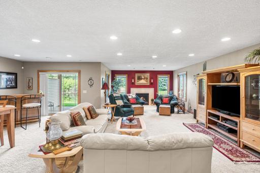 The lower-level family room features a gas fireplace, large windows overlooking the pond, and ample space for both living and entertaining