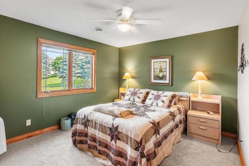 A spacious lower-level bedroom offers comfortable accommodations for family or guests, complete with a large window overlooking the backyard and pond.