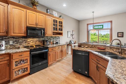 The kitchen was updated in 2020 and features new granite countertops, abundant cabinet storage, new stainless steel appliances, recessed lighting, and views toward the backyard through the informal dining area.