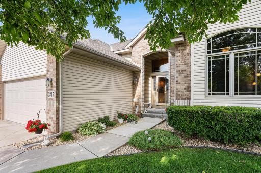 The inviting front entry showcases attractive brick accents, a covered porch, and professionally landscaped planting beds.
