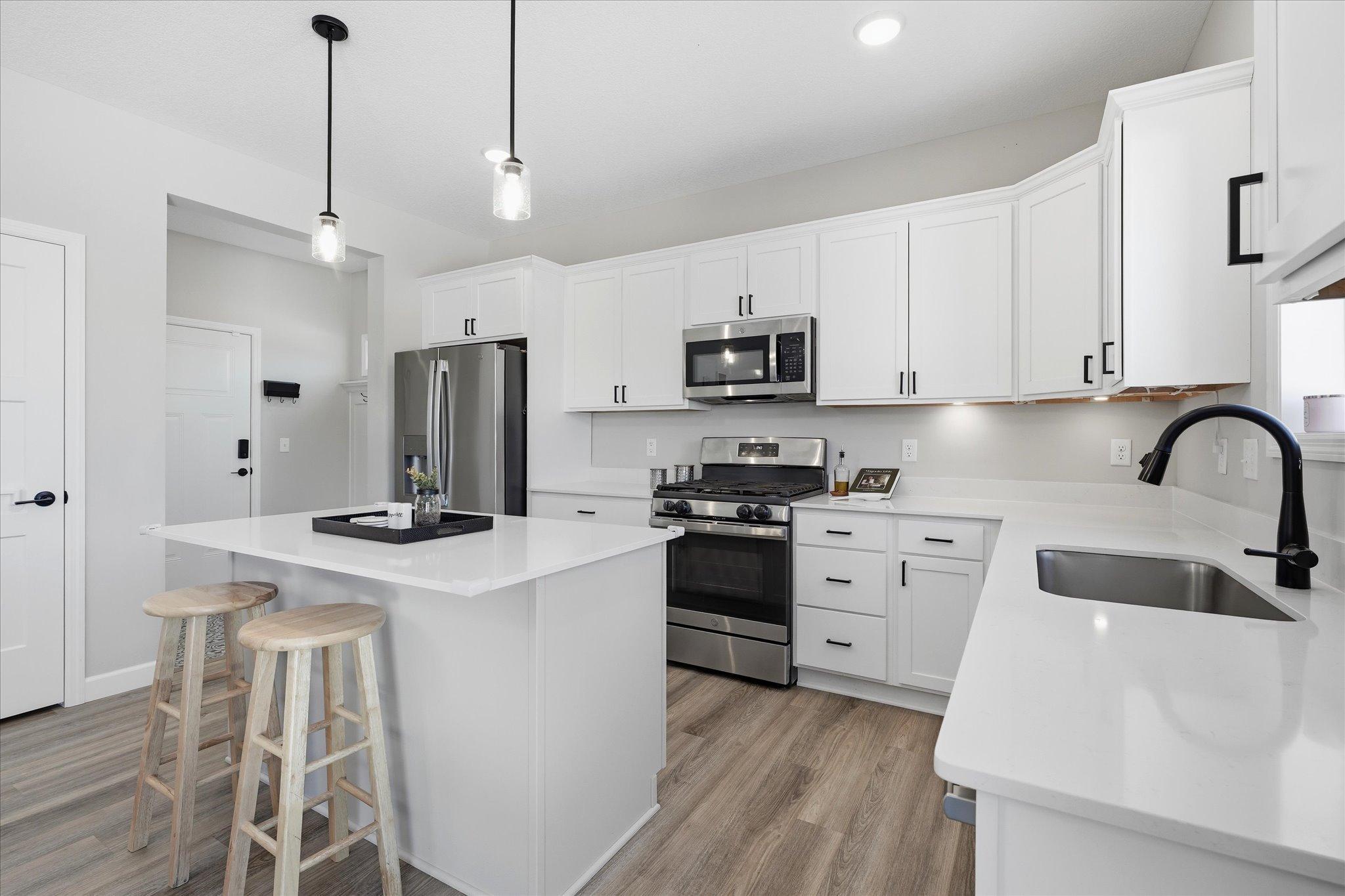 Quartz countertops, upgraded cabinetry, center island, pantry, and mudroom to garage