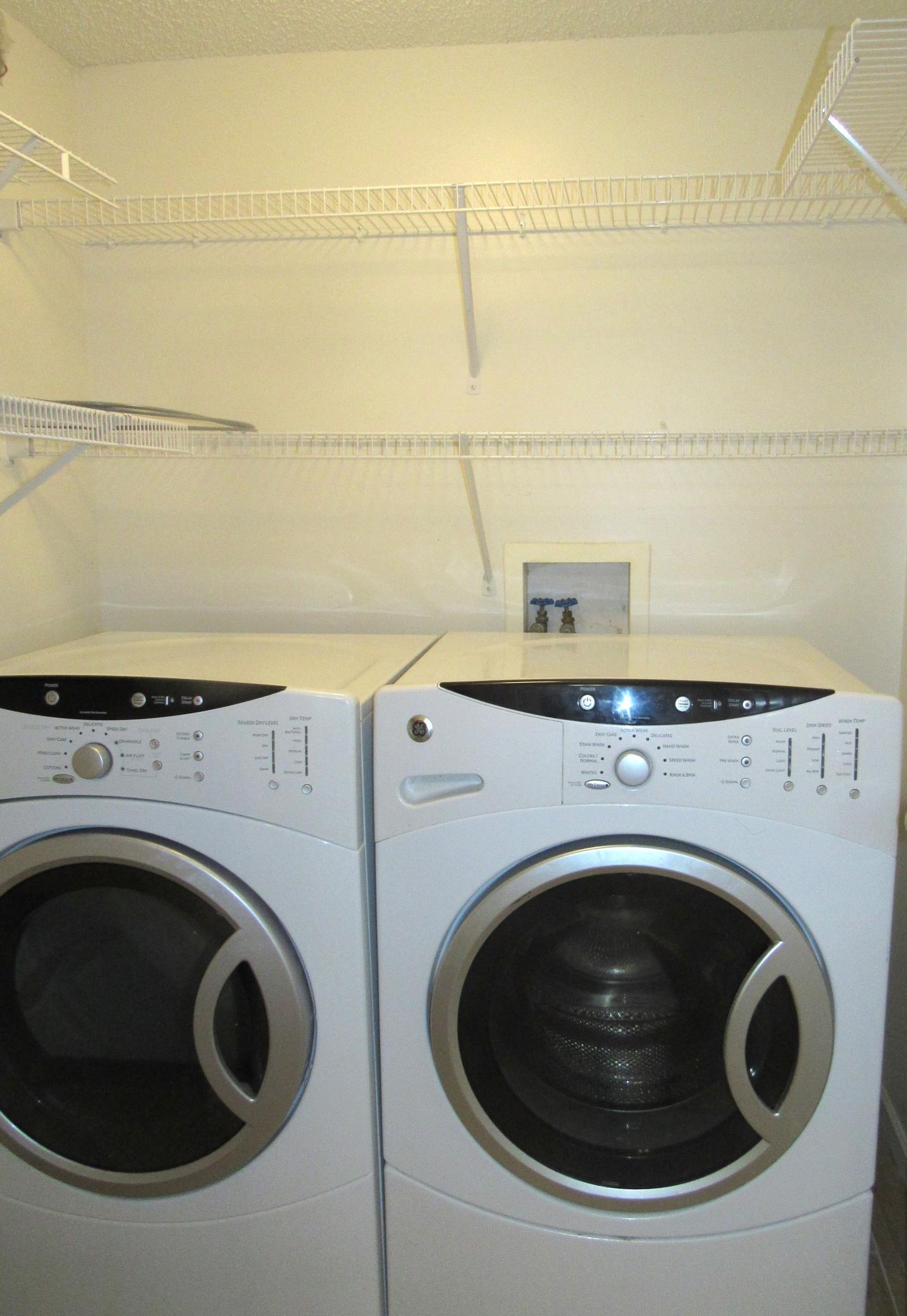 Laundry with GE washer and dryer, shelving and new tile floor.