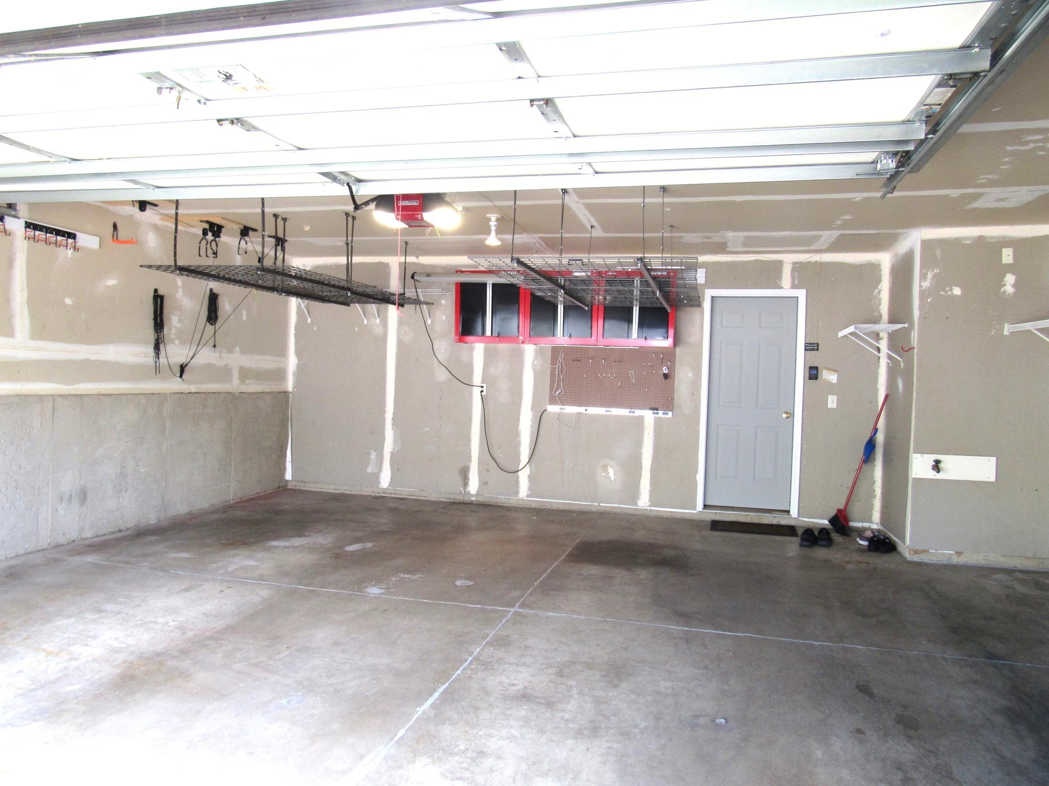 The garage has upper storage racks, Black and Decker and Craftsman cabinets, hooks, additional lighting and other shelving.