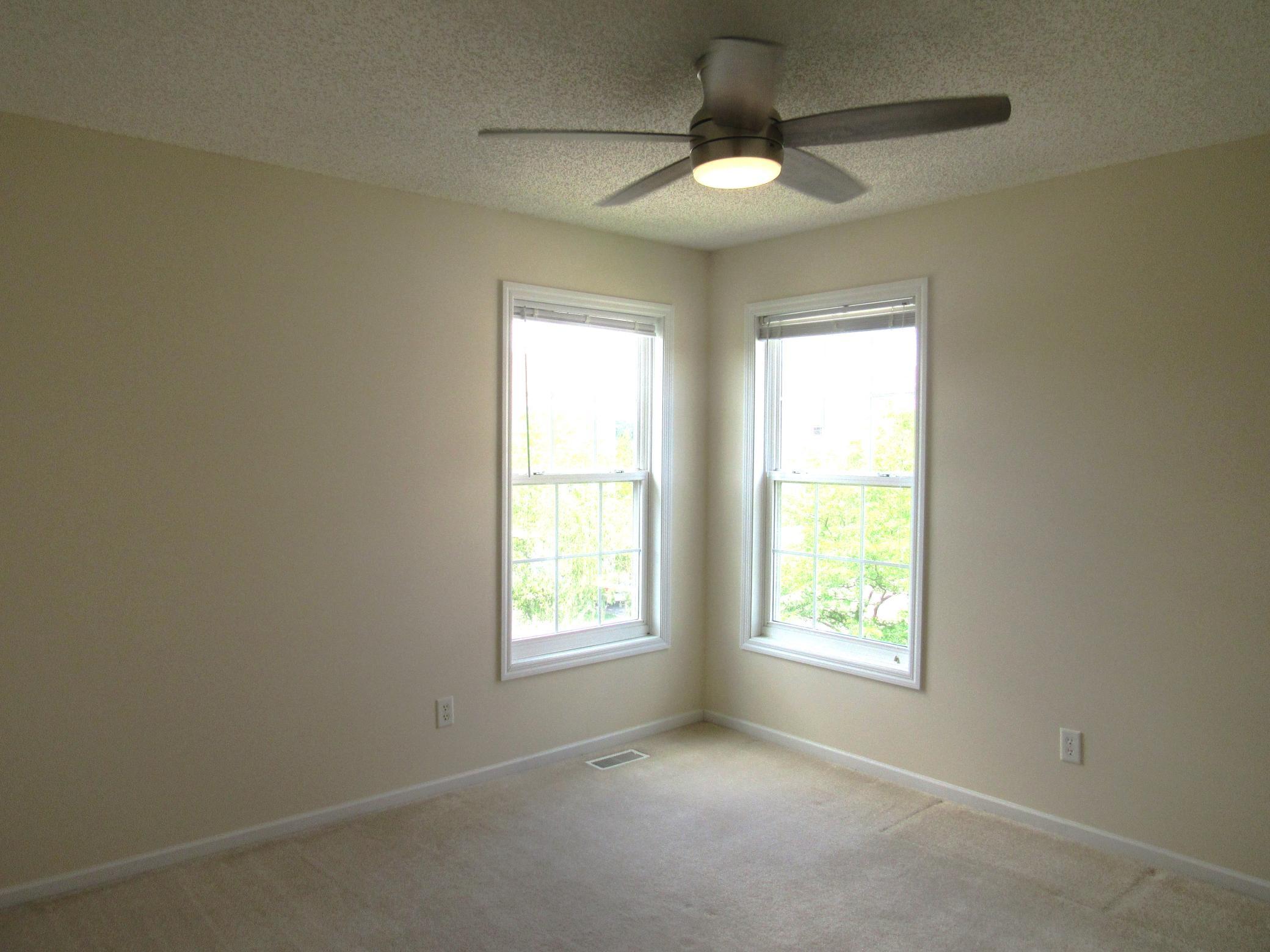 Bedroom 2 in the upper level with corner windows, walk-in closet and brushed nickel ceiling light with fan and remote. Freshly painted in a neutral color! 11.3x12.9