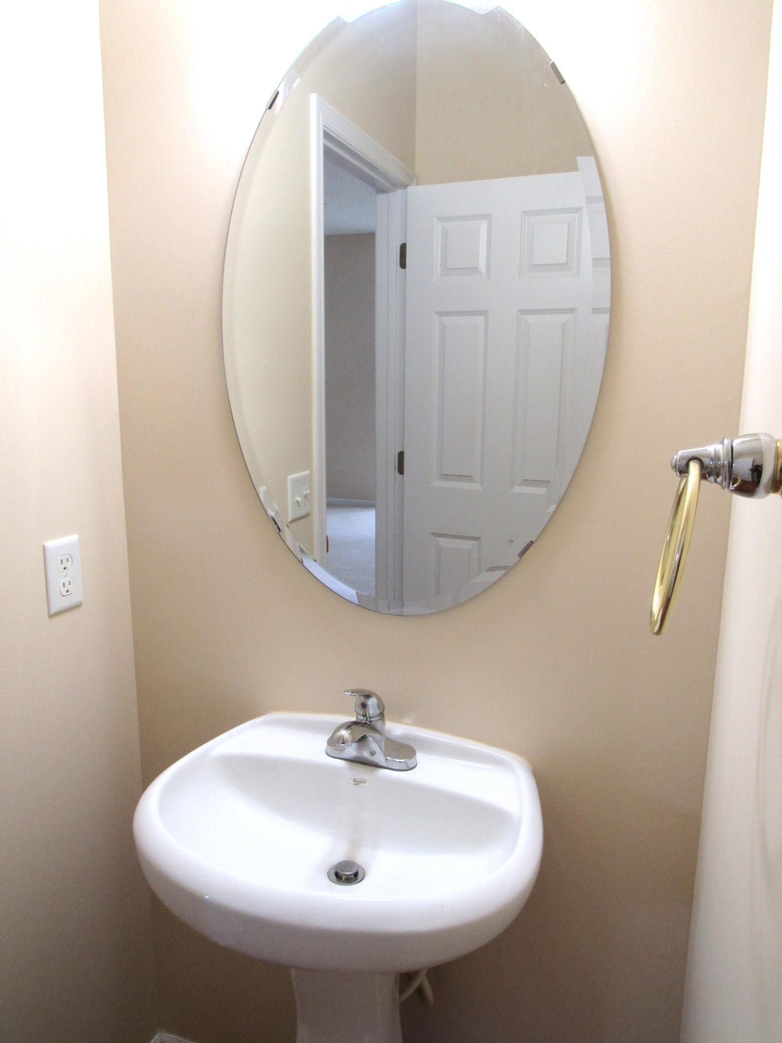 Partial view of the main floor 1/2 bath with a pedestal sink and attractive mirror.