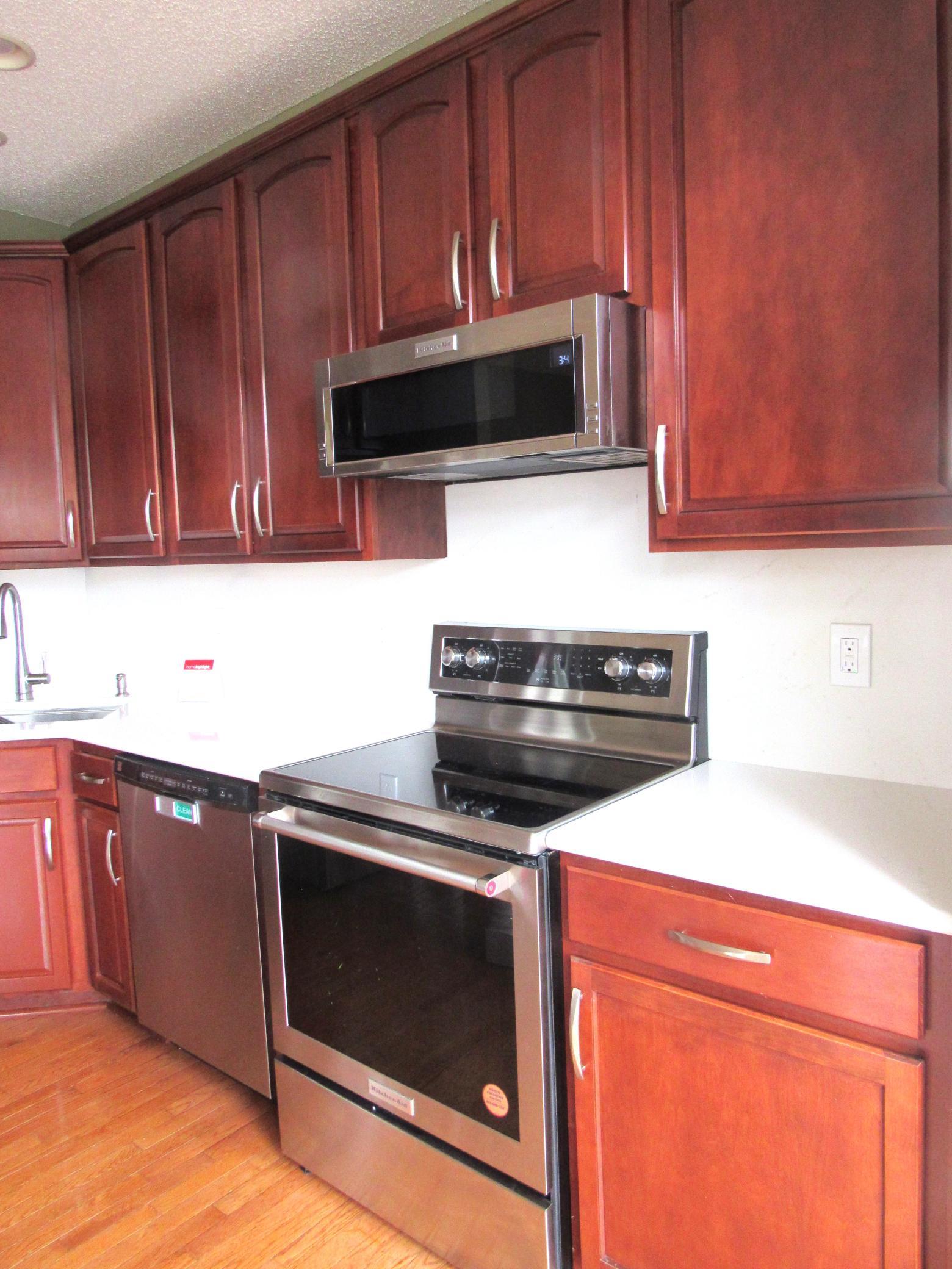Another view of the kitchen. Lots of cabinets, a pantry, center island and pull-out drawers. Updated quartz counters, faucet, sink and appliances.