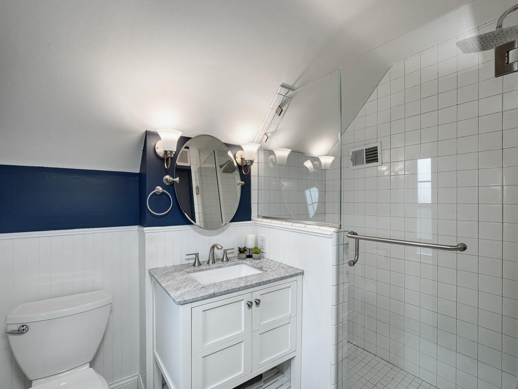 Stylish white tile and enclosed glass shower in the upper level bathroom.