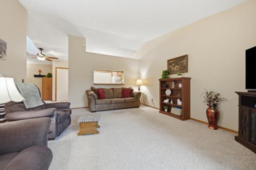 Spacious living room with vaulted ceilings and access to a private deck overlooking mature trees and green space