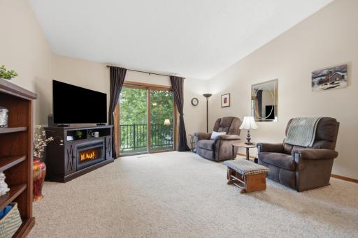 Spacious living room with vaulted ceilings and access to a private deck overlooking mature trees and green space