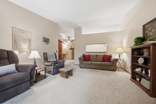 Spacious living room with vaulted ceilings and access to a private deck overlooking mature trees and green space