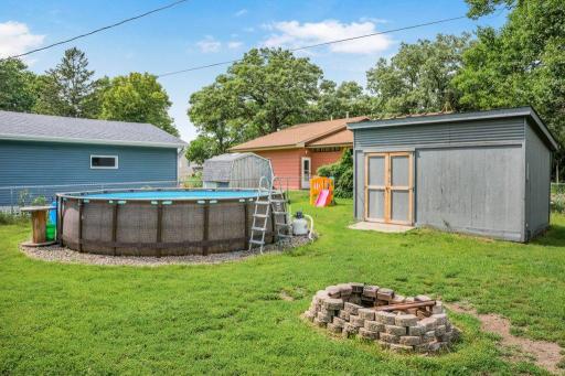 Private backyard featuring an above-ground pool, storage shed, fire pit, and plenty of space to relax, entertain, or simply enjoy the outdoors.