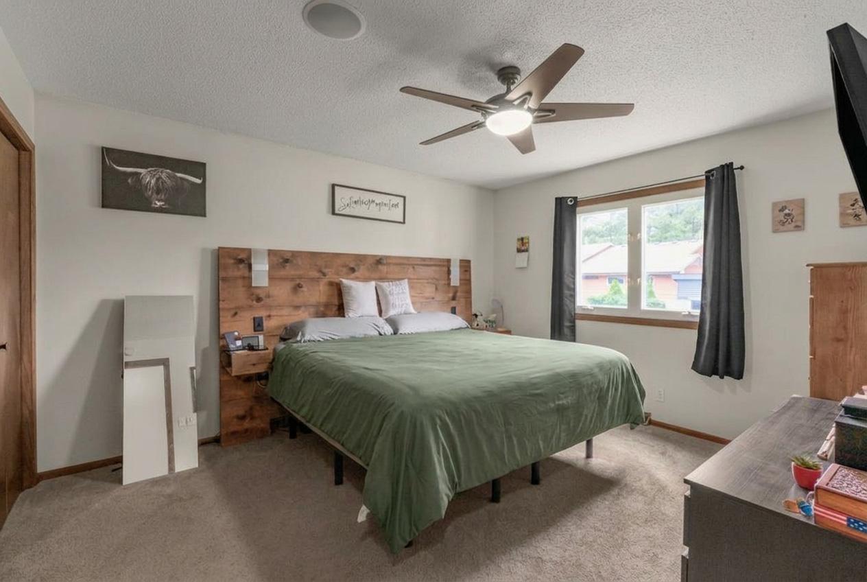 Spacious primary bedroom with room for a king-size bed, custom wood headboard, neutral finishes, abundant natural light, and plenty of space to relax and unwind.