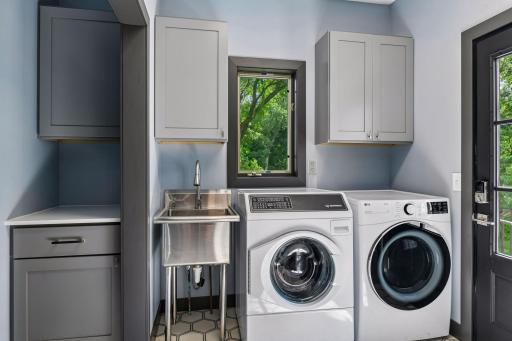 The remodeled laundry and mudroom area off the garage entry includes a utility sink, side-by-side washer and dryer, and built-in upper cabinetry for storage. Access door from laundry and mudroom leads you right out to maintanence free deck.