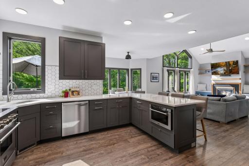 Updated cabinetry, a center peninsula, tile backsplash, and ample counter space complete the remodeled kitchen with a clean, modern finish.