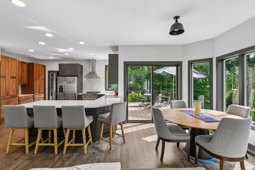 The open-concept kitchen and dining area opens to patio doors and the backyard deck, with a center island, pendant and recessed lighting, and a seamless connection to the living space.