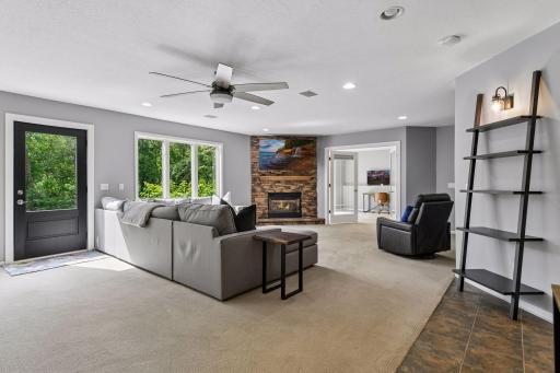 The lower-level family room continues with a stone gas fireplace, built-in shelving, and a walkout to the backyard, offering flexible space for gathering or recreation.
