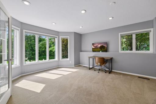 A versatile lower-level flex room with a wall of windows and walkout-level natural light, suited to an office, workout space, or hobby room.