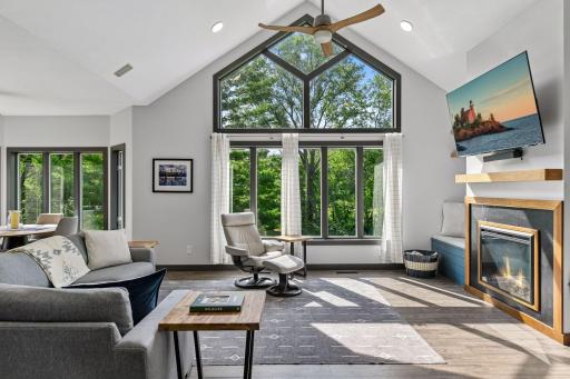 Expansive windows and soaring ceilings create a bright, open gathering space with wooded views and a connected main-floor layout.