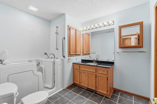 Main level full bathroom featuring tile flooring, granite countertop and a custom walk-in bathtub designed for easy entry and jets to melt away the dayâs stress.