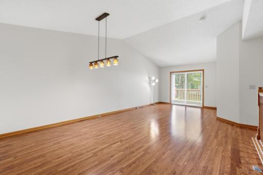 Main level living room with vaulted ceiling and patio door that leads to the deck