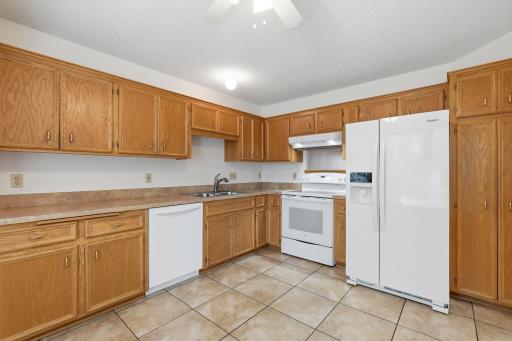 Bright eat-in kitchen features a bay window, tile flooring and a pass-through to the dining room