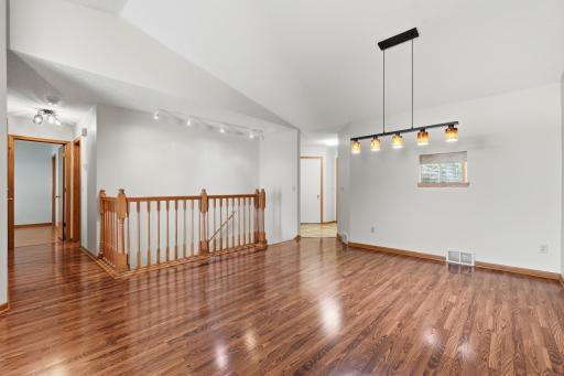 Reverse view of main level living room, dining room, and wood banister stairway.