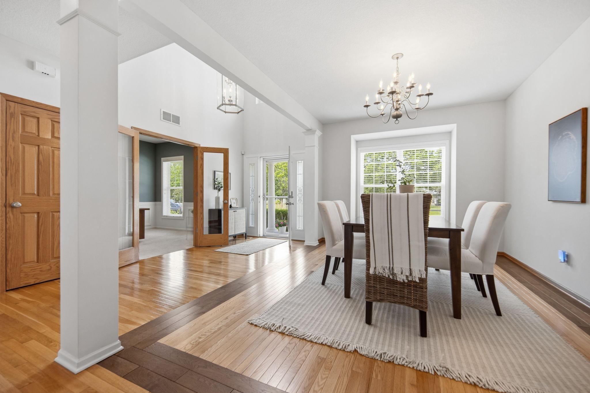 The formal dining room features immaculate oak floors bordered by rich Brazilian walnut trim, creating a warm and sophisticated ambiance beneath a beautiful chandelier.
