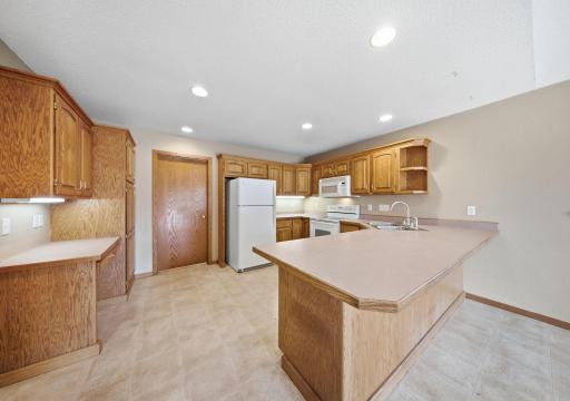 The spacious kitchen offers a breakfast bar, abundant cabinetry, a built-in desk area, and a seamless connection to the dining area. (virtually staged)