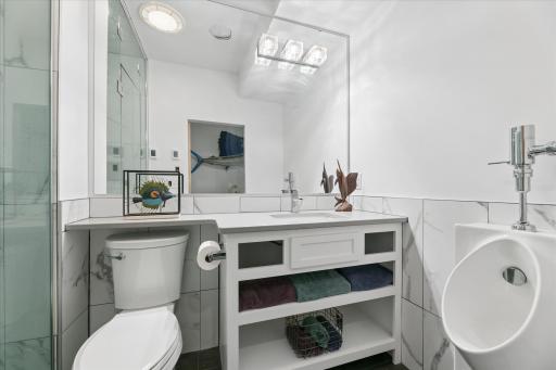 Lower level bathroom featuring steam shower, urinal, and heated tile floors.