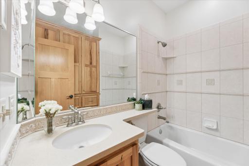 Main level full bathroom. Tile flooring and tile shower surround. Oversized built-in linen cabinets and toiletry storage.