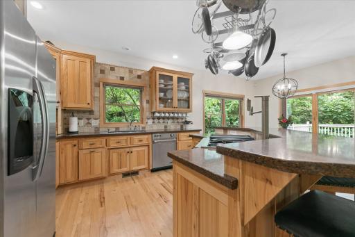 Bountiful counters space for meal-prep and dining. Travertine tile backsplash beautifully blends with Silestone counters. Thoughtful designs include appliance garage, glass display cabinet and undermount mug storage and deep double-sink.
