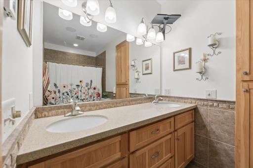 Private primary bathroom featuring heated tile floors, dual vanity sinks and abundant toiletry & linen storage. Bright lighting for makeup, stone countertops and tile backsplash. Built-in speakers for music.