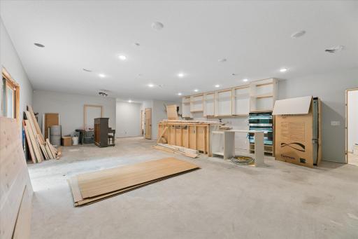 Semi-finished walkout lower level with the start of a full kitchen, including standard refrigerator, built-in oven/microwave, sink and dishwasher. All appliances are new & still wrapped. Cabinet boxes installed, leftover finish-materials may stay.