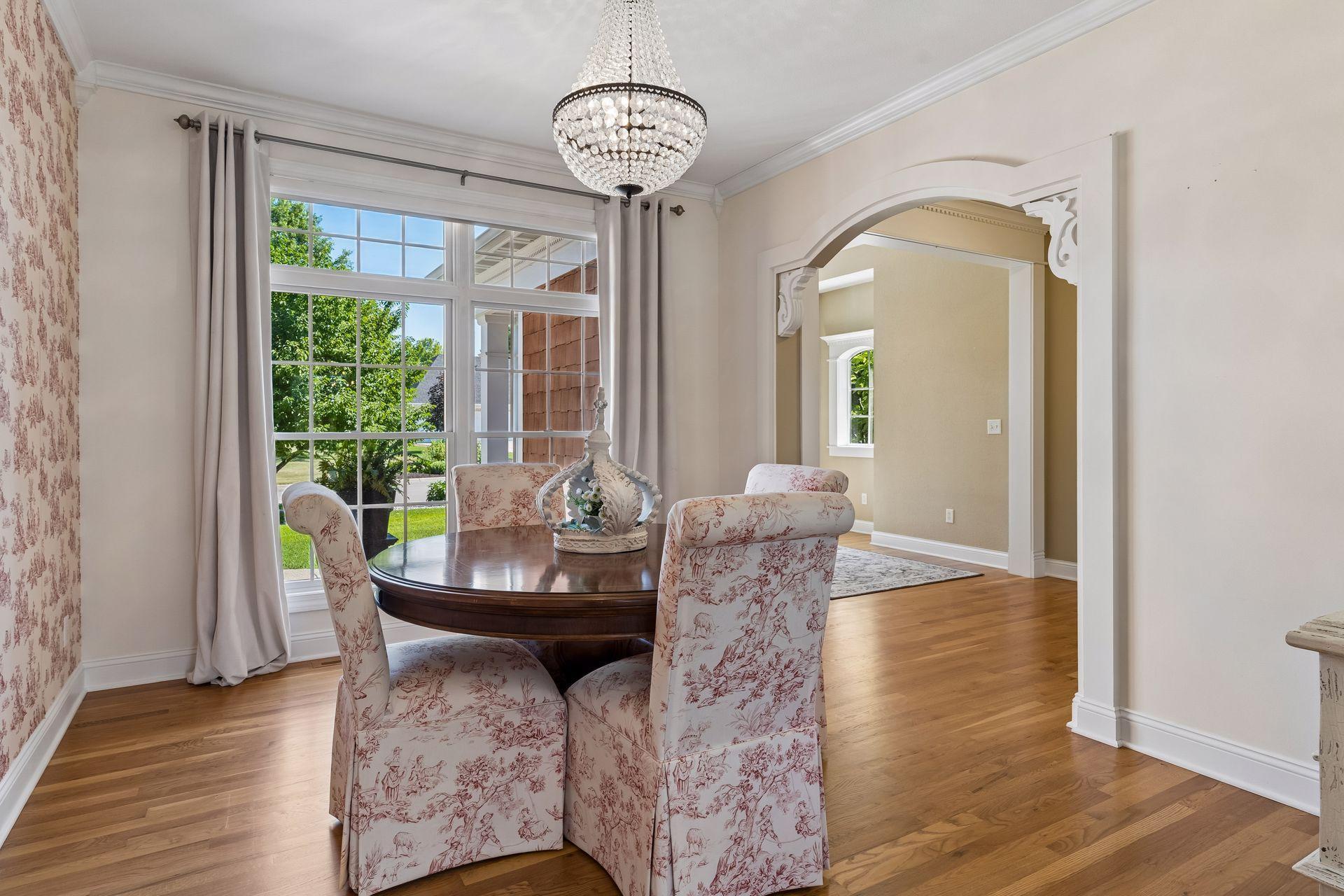 Elegant Formal Dining Room featuring hardwood floors, crown molding, a decorative archway, and large windows that fill the room with natural light.