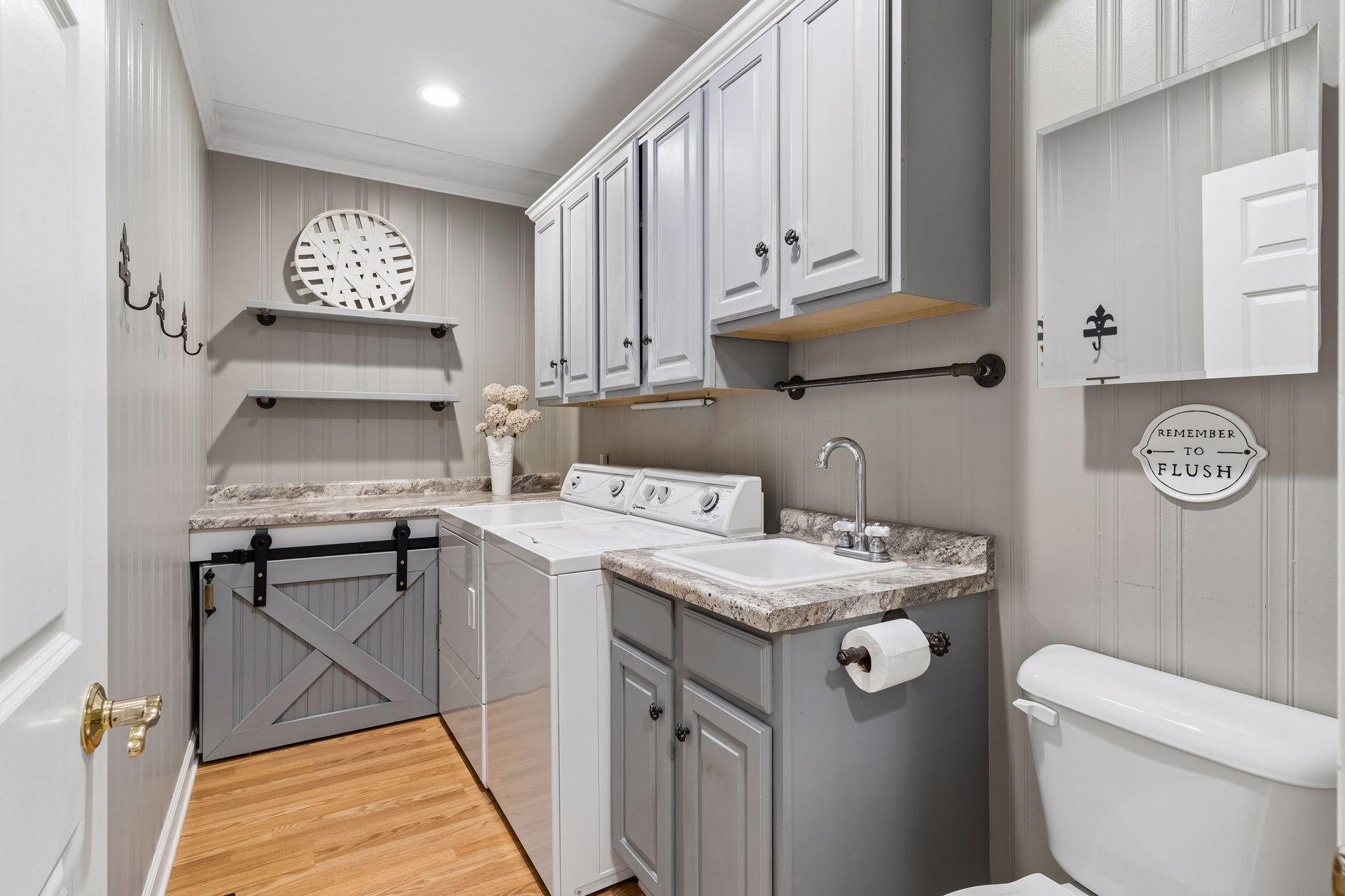Main Floor Laundry Room has built-in cabinetry, utility sink, folding counter, additional storage, and a convenient Half Bath.