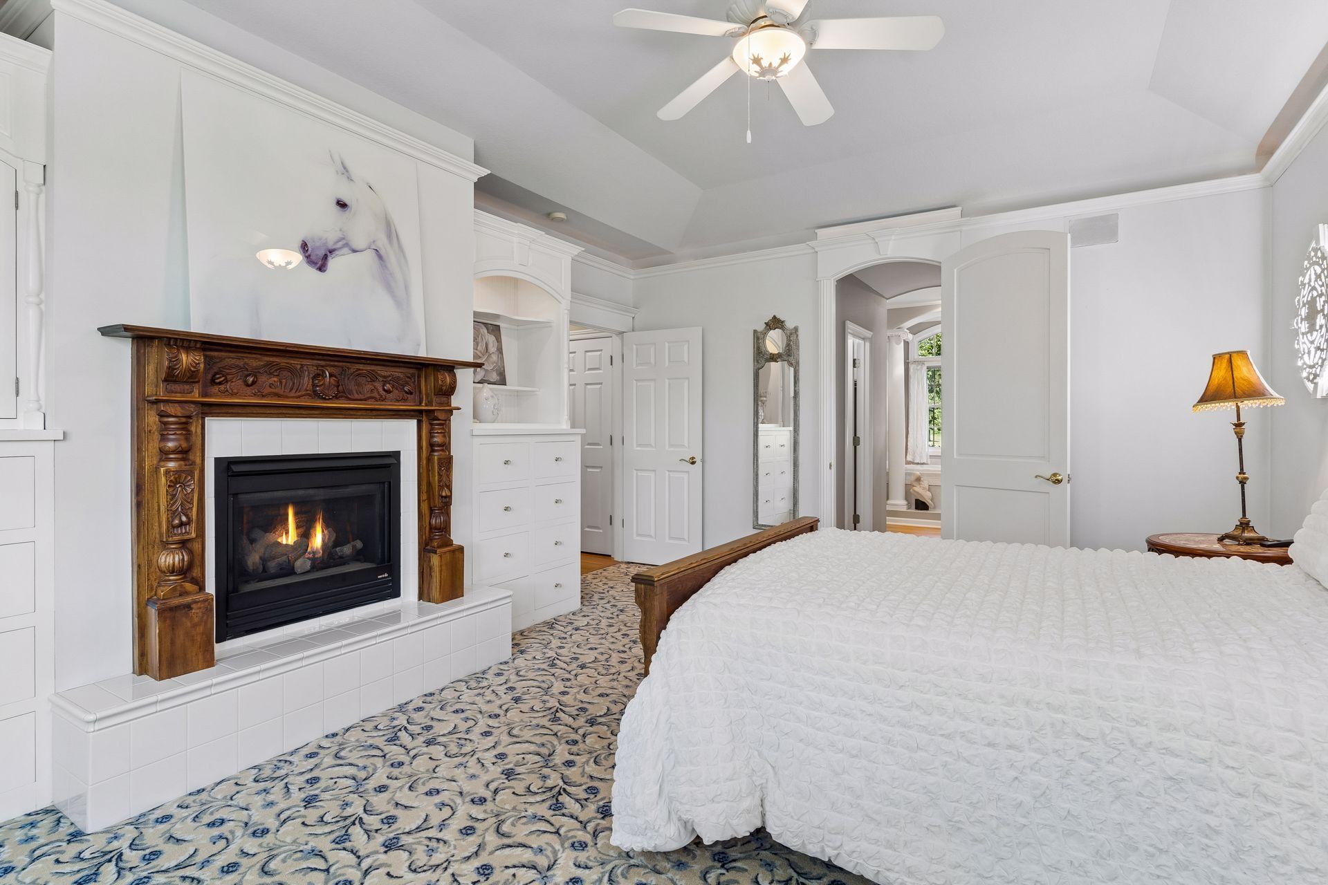A second view of the Main Level Owner's Suite shows the built-in cabinetry, antique Fireplace mantel surrounding the Gas Fireplace, and private entrance to the remodeled Owner's Bath.