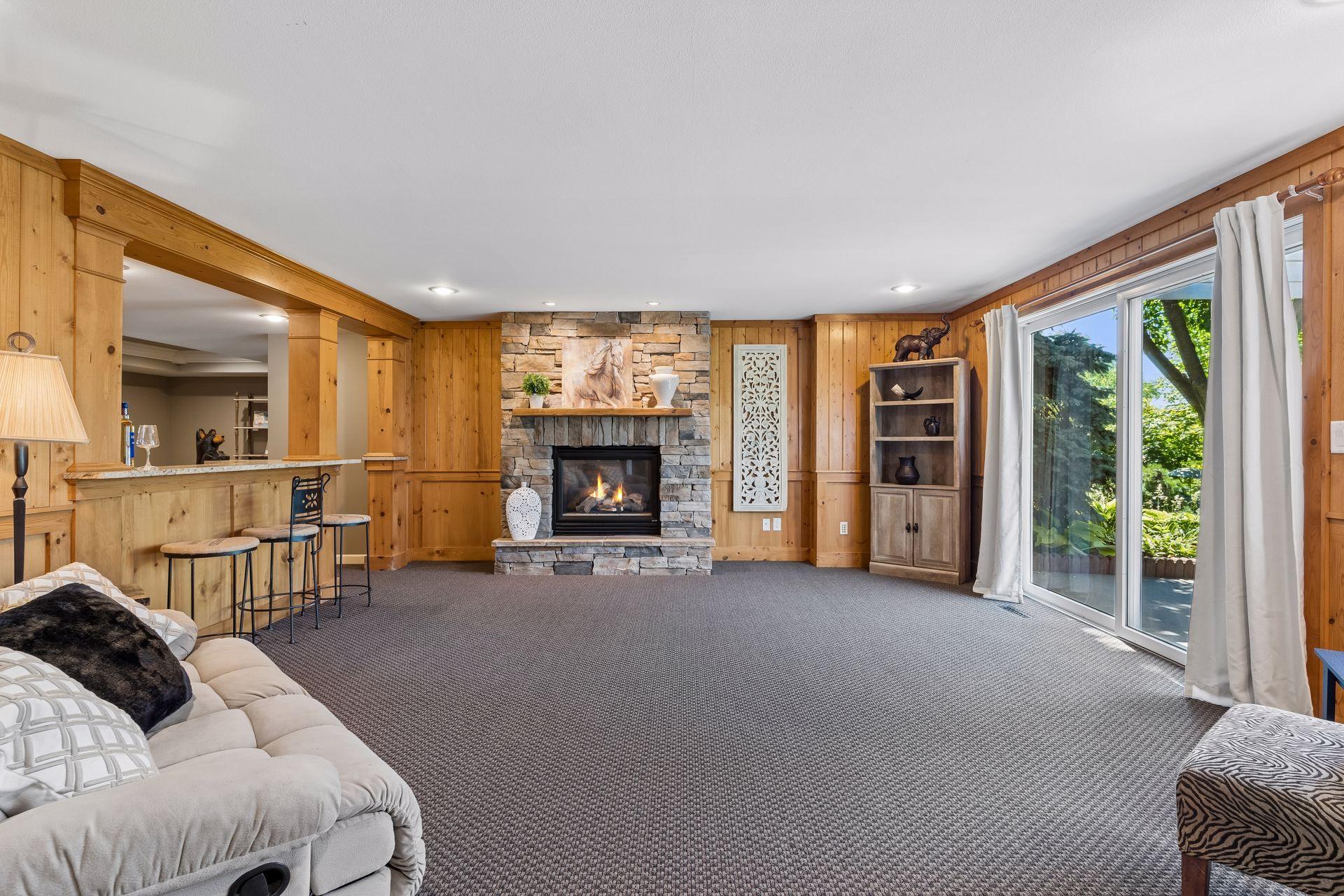 The walkout lower level offers another expansive gathering space with a stone Gas Fireplace, wet bar, and direct access to the pergola-covered patio.