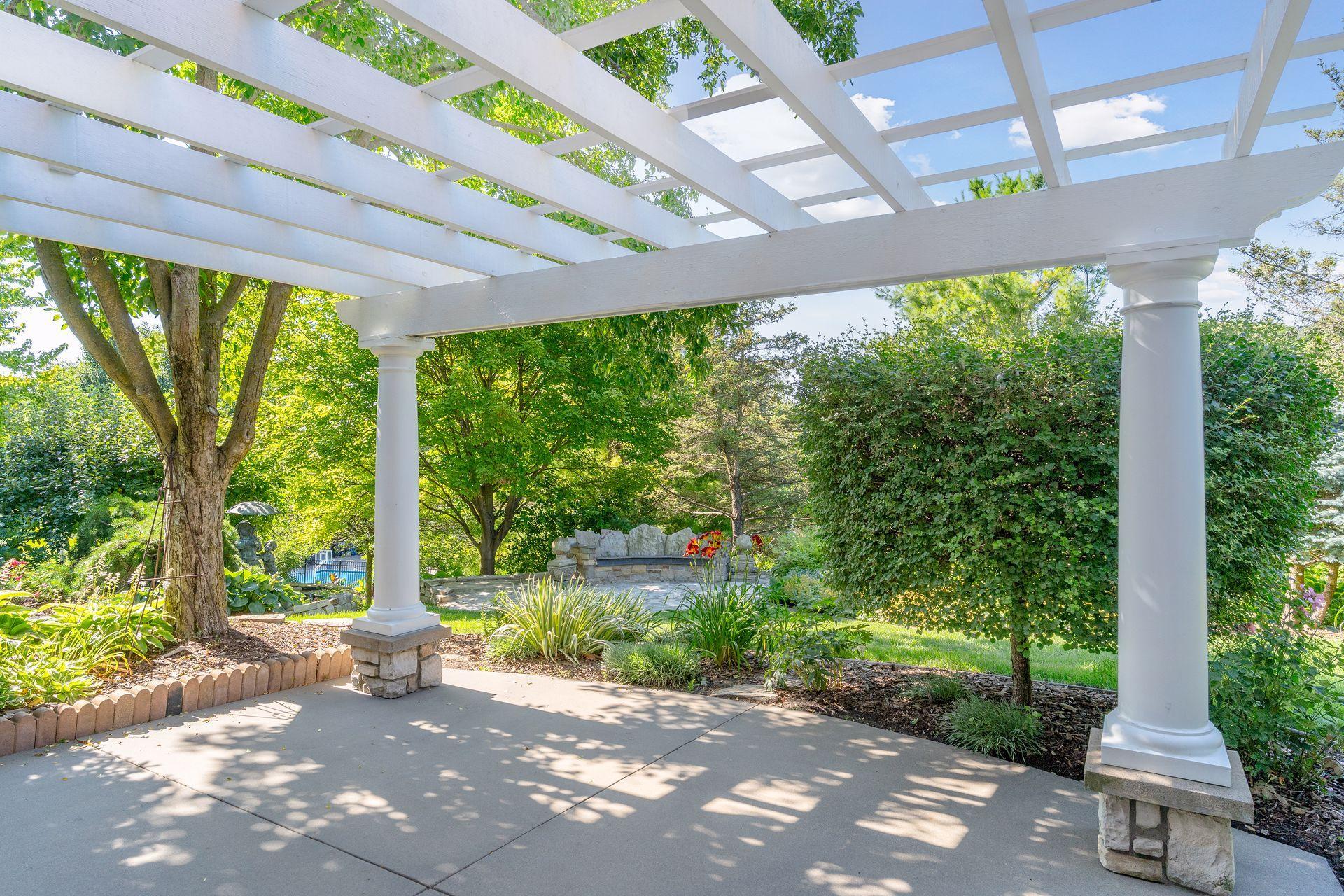 Relax beneath the pergola while overlooking the peaceful pond and custom seating area.