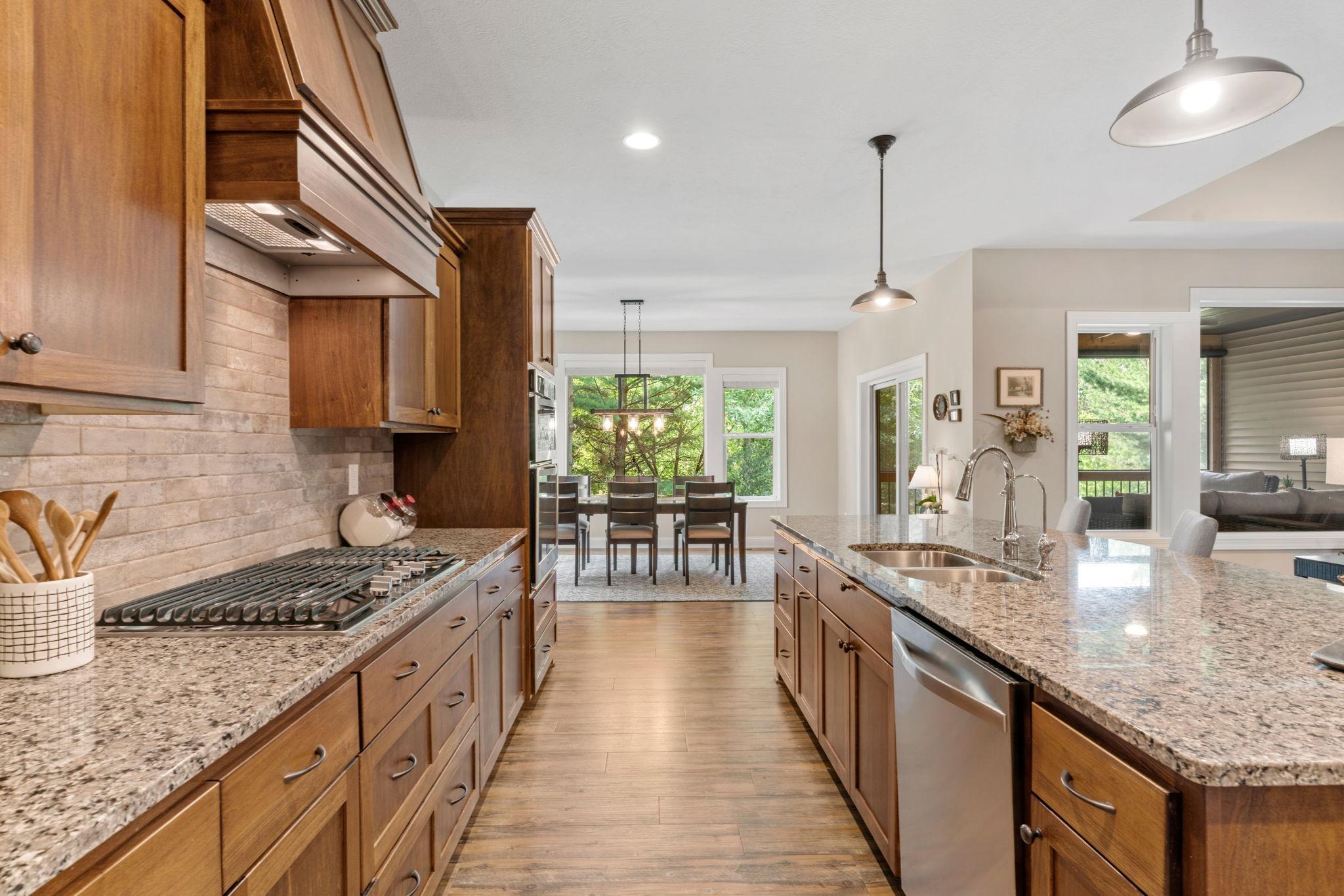 Gourmet Kitchen w/ granite counters, oversized island, SS apps, 5-burner gas cooktop, RO water system, cabinet pull-outs & walk-in pantry