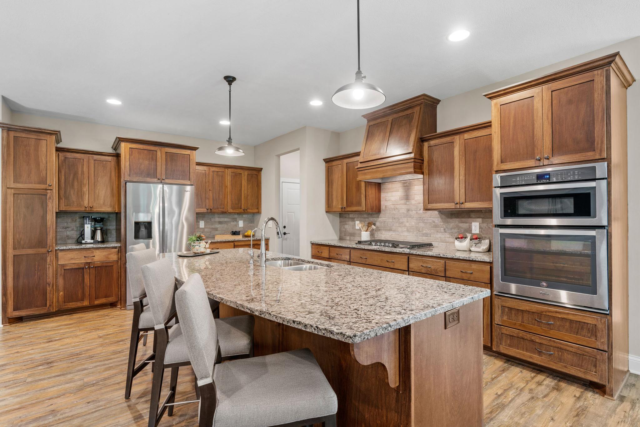 Gourmet Kitchen w/ granite counters, oversized island, SS apps, 5-burner gas cooktop, RO water system, cabinet pull-outs & walk-in pantry