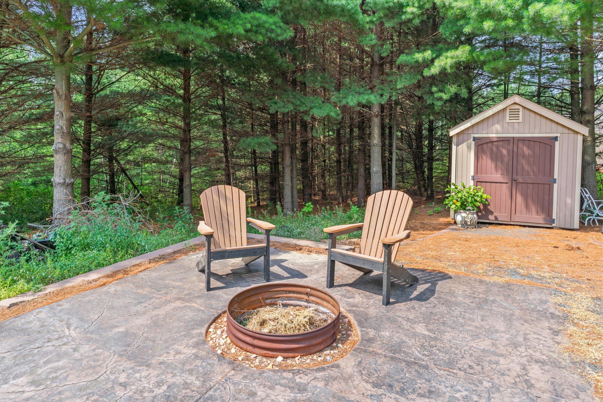 ncredible outdoor retreat w/ stamped concrete patio, built-in FP, expansive flat yard & peaceful wooded setting