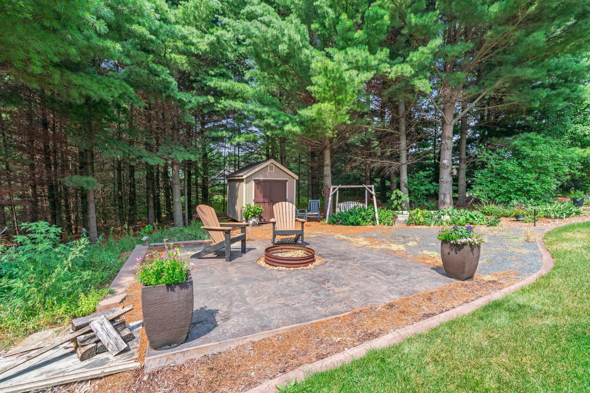 ncredible outdoor retreat w/ stamped concrete patio, built-in FP, expansive flat yard & peaceful wooded setting